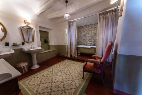 Elegantes Badezimmer in La Bouscatière mit Doppelwaschtischen auf Sockeln, Badewanne, gemusterter Tapete und klassischen Möbeln