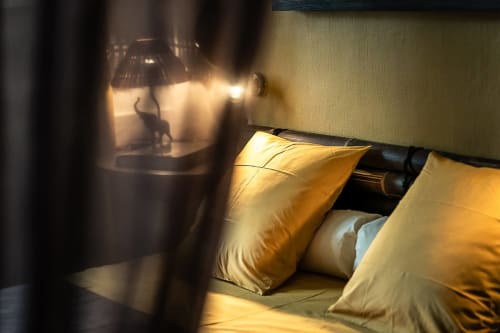 Gemütliches römisches Zimmer in La Bouscatière mit goldenen Kissen, warmer Lampenbeleuchtung und eleganten Fenstervorhängen