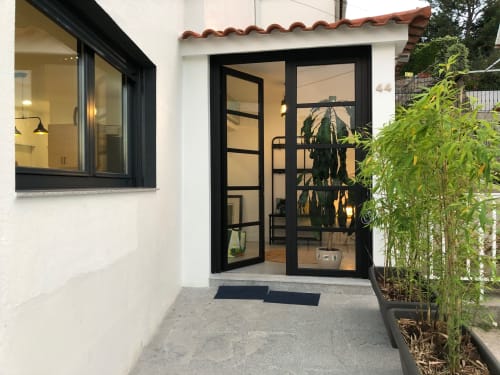 Entrada de la villa Casa Arealonga en Vigo con puertas de cristal de marco negro moderno y paredes blancas