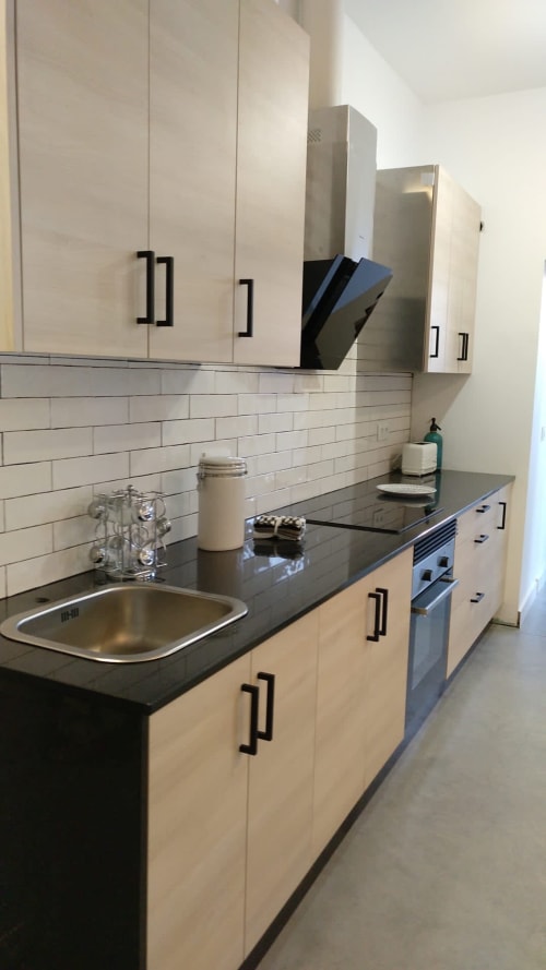 Cocina moderna en villa Casa Arealonga de Vigo con muebles color crema, encimera oscura, azulejos metro y acero inoxidable