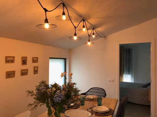 Comedor de la villa Casa Arealonga en Vigo con iluminación colgante, obras de arte enmarcadas y mesa elegantemente decorada