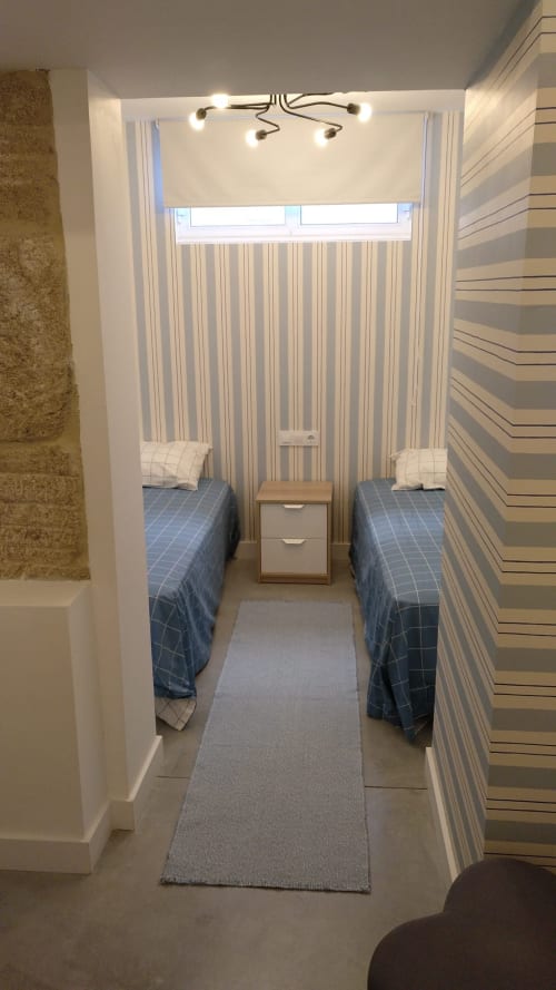 Habitación doble con paredes a rayas, colchas azules e iluminación cenital en la villa Casa Arealonga de Vigo