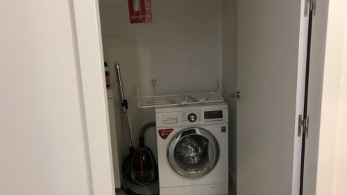Lavadero de la villa Casa Arealonga en Vigo con lavadora blanca, tendedero y productos de limpieza