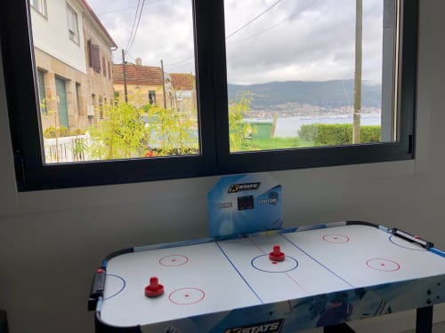 Mesa de aire hockey en la villa Casa Arealonga de Vigo con vistas panorámicas de la bahía y la ciudad costera a través de la ventana