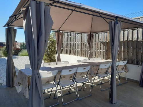 Pérgola para comedor al aire libre en Casa Rural La Perla con mesa, sillas y cortinas colgantes en Hiendelaencina