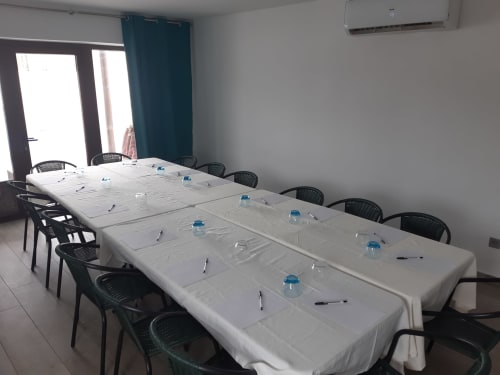 Sala de conferencias en Casa Rural La Perla en Hiendelaencina con mesa blanca alargada, sillas negras y botellas de agua