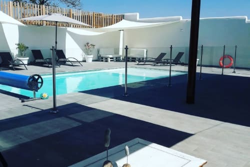 Moderna zona de piscina en Casa Rural La Perla en Hiendelaencina con tumbonas, estructuras de sombra blancas y agua turquesa