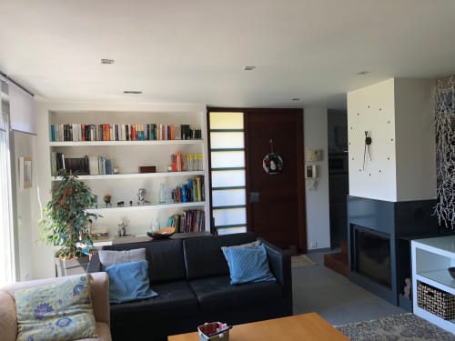 Sala de estar moderna en Casa Arealonga de Vigo con sofá negro, estanterías empotradas, chimenea y puerta de madera oscura
