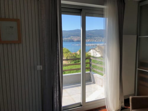 Moderno dormitorio con puertas correderas de cristal con vistas a la bahía de Vigo y las montañas desde Casa Arealonga