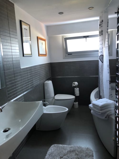 Baño moderno en Casa Arealonga de Vigo con paredes de azulejos oscuros, accesorios blancos y decoración minimalista