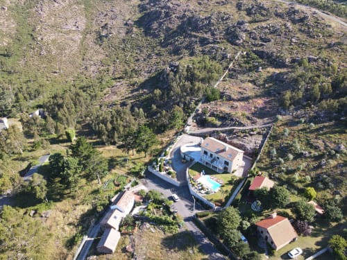 Vista aérea del hotel A Ballenera de Caneliñas en Cee, España, rodeado de bosques y montañas con piscina