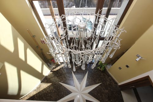 Elegante araña de cristal en la entrada del hotel A Ballenera de Caneliñas en Cee, España, con tragaluz y piso de baldosas modernas.