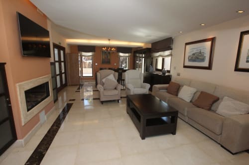 Elegante salón de hotel en A Ballenera de Caneliñas en Cee con asientos beige, chimenea y muebles de madera oscura