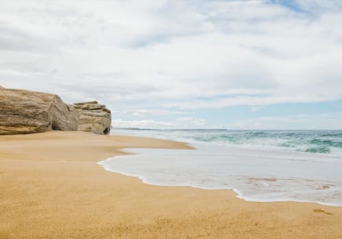 Praia serena com areia dourada, ondas suaves e formações rochosas dramáticas perto de Óbidos, Portugal