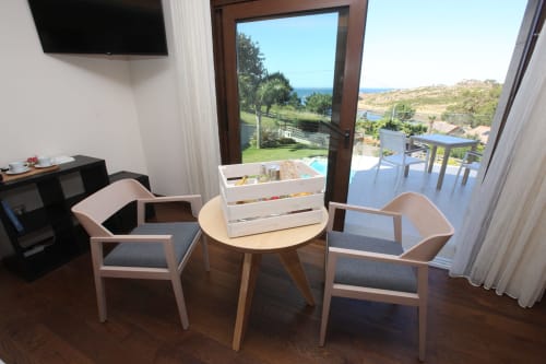 Habitación moderna del hotel A Ballenera de Caneliñas en Cee con zona de estar con vistas al jardín costero y piscina