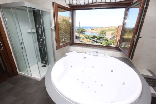 Lujoso baño con bañera de hidromasaje redonda y vistas al océano en el hotel A Ballenera de Caneliñas en Cee, España