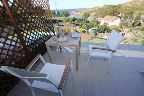 Zona de comedor en terraza del hotel A Ballenera de Caneliñas en Cee con vistas al mar, celosía de madera y paisaje costero.