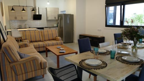 Apartamento moderno diáfano Casa Arealonga Vigo con sofá rayado, mesa de comedor, cocina y electrodomésticos de acero inoxidable.