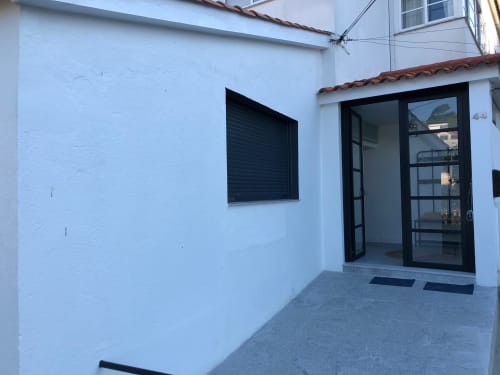 Terraza de Casa Arealonga en Vigo con muros blancos, contraventanas negras y puertas de cristal