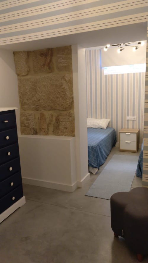 Dormitorio moderno en Casa Arealonga, Vigo con cama, cortinas a rayas, tabique divisorio e iluminación contemporánea