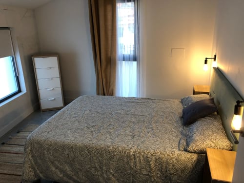 Dormitorio moderno del hotel Casa Arealonga en Vigo con cama de matrimonio, lámparas de noche y balcón con puerta de cristal con vistas a la ciudad