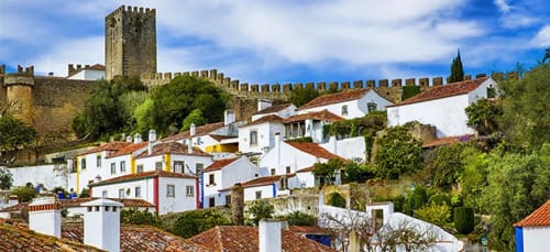Medieval castle overlooking white-washed houses in Óbidos, Portugal - Kindnessmoon guesthouse