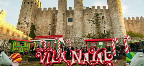 Christmas market stalls with candy decorations in front of Óbidos medieval castle, Portugal