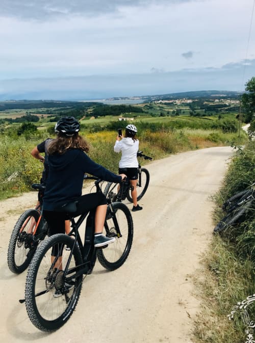 Two cyclists on dirt road with scenic valley views near Óbidos, Portugal
