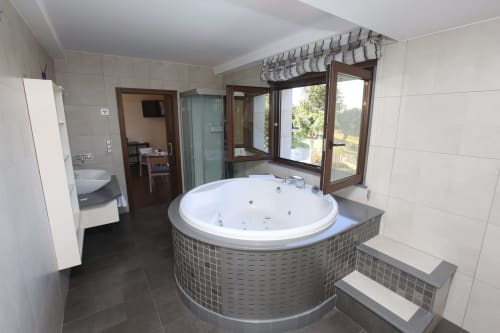 Baño de lujo en la habitación Temerario del hotel A Ballenera de Caneliñas en Cee con bañera de hidromasaje circular, vistas al mar y diseño moderno