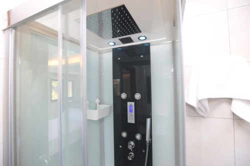 Panel de ducha negro moderno con controles digitales y alcachofa de lluvia en la habitación Temerario del hotel A Ballenera de Caneliñas