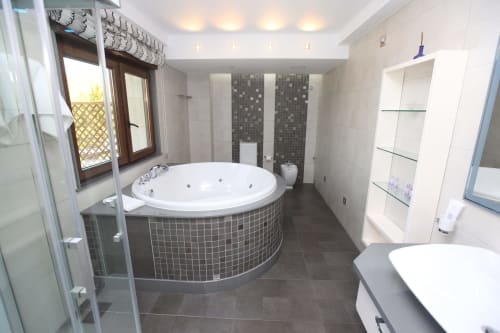 Lujoso baño en hotel A Ballenera de Caneliñas con bañera de hidromasaje circular, ducha de lluvia y acabados modernos en Cee