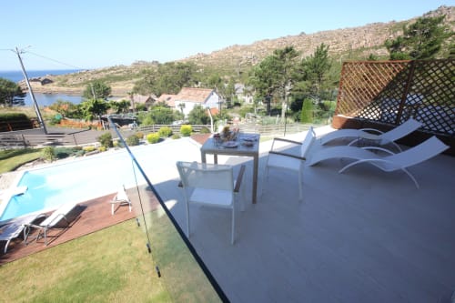 Balcón de la habitación Temerario en A Ballenera de Caneliñas, Cee con vistas al mar, tumbonas, piscina y paisaje costero