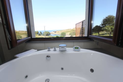 Lujosa bañera de hidromasaje con vistas al mar hacia la costa de Cee, España, en el hotel A Ballenera de Caneliñas