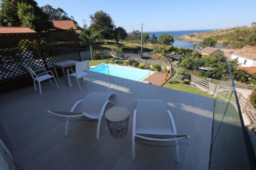 Balcón de hotel costero con tumbonas, piscina y vistas al mar en Cee, Galicia