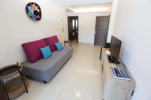 Salón moderno en la habitación Lobeiro de A Ballenera de Caneliñas en Cee con sofá gris, TV y balcón con vistas al mar