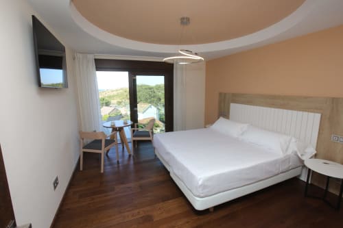 Habitación Lobeiro del hotel A Ballenera de Caneliñas en Cee con balcón con vistas al mar, cama moderna y mobiliario contemporáneo