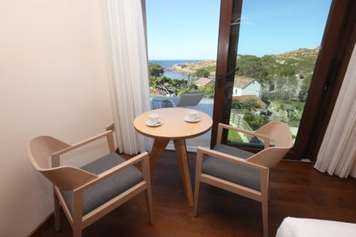 Habitación Lobeiro en A Ballenera de Caneliñas con vistas al mar, sillas modernas, mesa redonda y paisaje costero de Cee, España