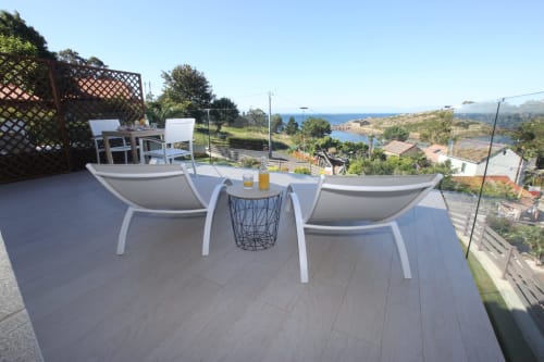 Terraza moderna con tumbonas blancas con vistas a la bahía costera del hotel A Ballenera de Caneliñas, Cee