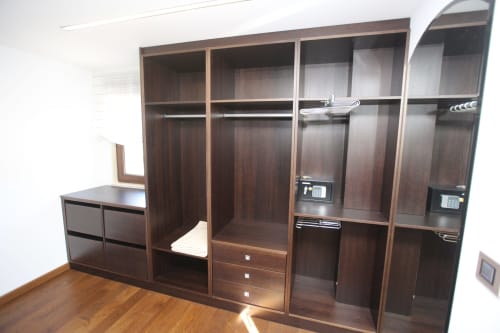 Armario empotrado de madera con estantes, cajones y barras de ropa en la habitación Lobeiro del hotel A Ballenera de Caneliñas