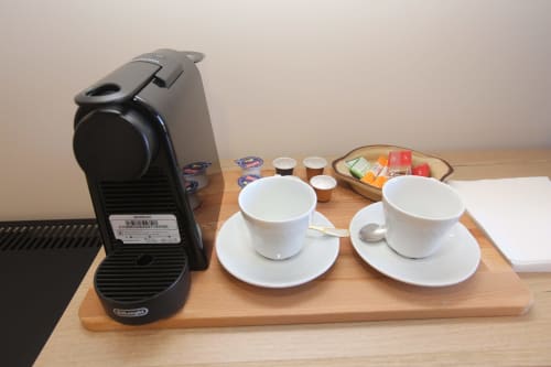 Cafetera Nespresso con dos tazas blancas y platillos sobre bandeja de madera en el hotel A Ballenera de Caneliñas en Cee