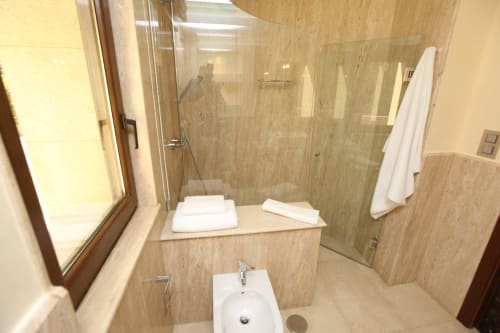 Baño moderno con plato de ducha, toallas blancas y baldosas beige en el hotel A Ballenera de Caneliñas en Cee, España