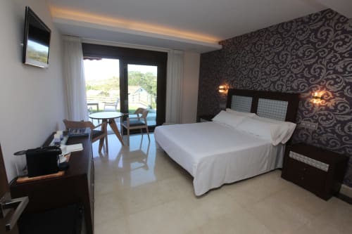 Habitación Carrumeiro del hotel A Ballenera de Caneliñas en Cee con vistas al mar, cama y acceso a balcón