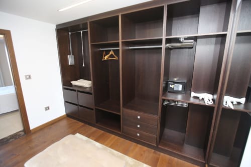 Amplio vestidor con muebles de madera oscura, perchas, cajones y almacenamiento en la habitación Carrumeiro de A Ballenera de