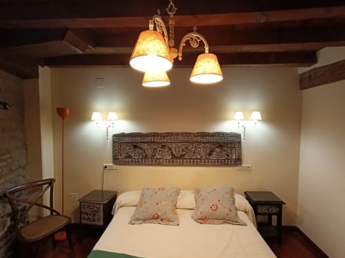 Elegante dormitorio en La Posada Del Tietar con cabecero decorativo, lámparas colgantes y muebles tradicionales