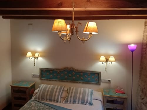 Acogedora habitación de La Posada Del Tiétar con vigas de madera, apliques de latón, almohadas rayadas y arte decorativo en cabecero