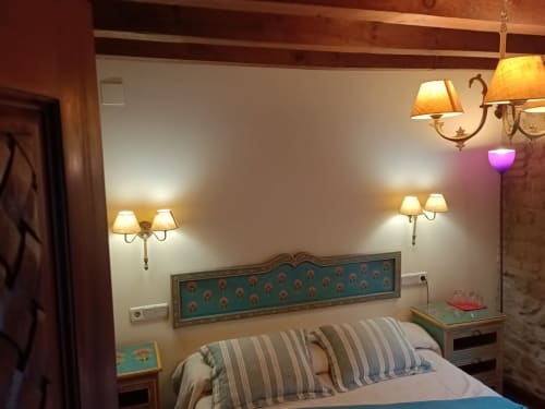 Acogedora habitación en La Posada Del Tietar con cabecero turquesa, almohadas a rayas, apliques de pared e iluminación cálida