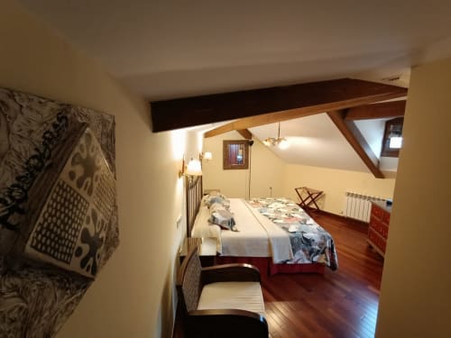 Acogedor dormitorio en buhardilla de La Posada Del Tietar con vigas de madera, piedra vista, suelos de parqué y vistas a la ciudad