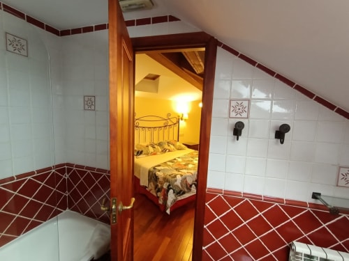 Entrada del dormitorio en La Posada Del Tietar, Santa María del Tiétar, mostrando cama a través de puerta de madera y piso de azulejos rojos