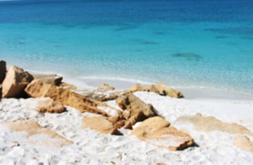 Spiaggia sabbiosa con rocce dorate e acqua turchese a Torre Grande, Oristano, Italia