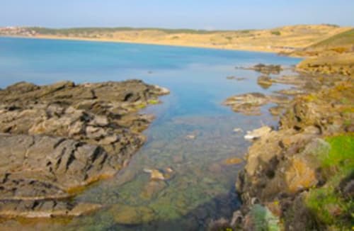 Piccola insenatura rocciosa con acque turchesi vicino a Torre Grande, Oristano, Italia